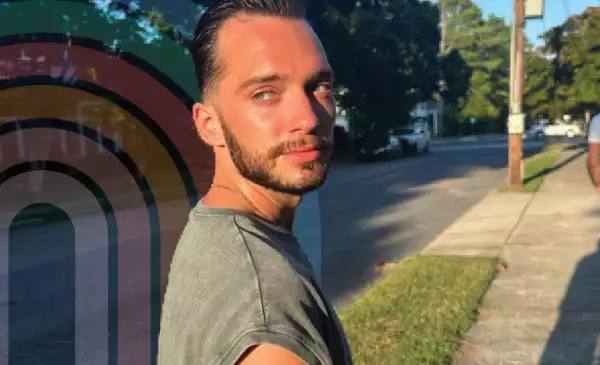 Closeup of a male presenting person walking on the sidewalk looking back at the camera