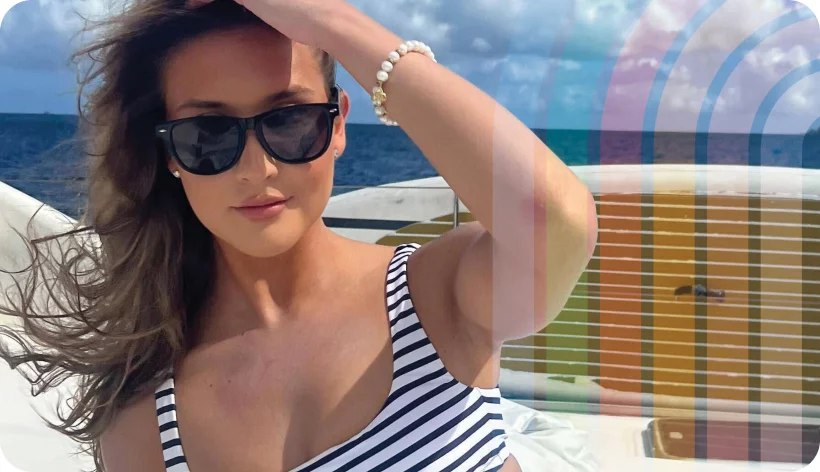Female presenting person at the beach wearing sunglasses