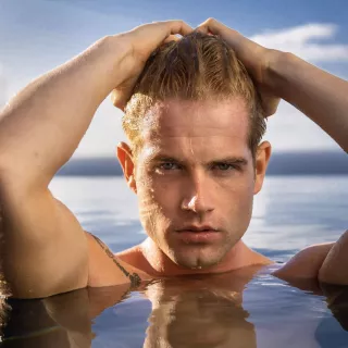 Tanned shirtless man rising out of a pool