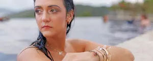 A woman rests her arm on the edge of a pool and stares into the distance.