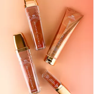 Four Crystal Sunshine tanning and beauty products from Palm Beach Tan’s Premier Collection arranged on a peach background.