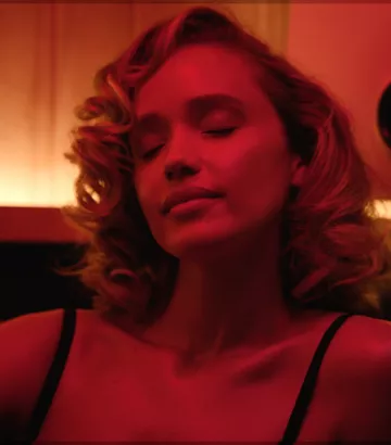 Close‑up portrait of a woman with her eyes closed, bathed in warm red lighting.