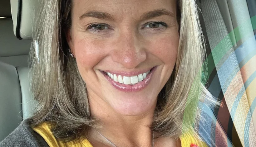 Female presenting person with shoulder length hair smiling in the car