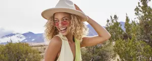 Smiling female presenting person in pink sunglasses and a bright green top