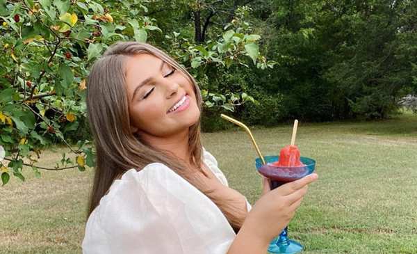 Woman in a white dress out in nature with a drink