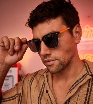 A male presenting person in a striped shirt wearing sunglasses